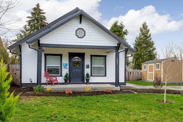 bungalow-style home featuring a storage shed, a front lawn, and covered porch