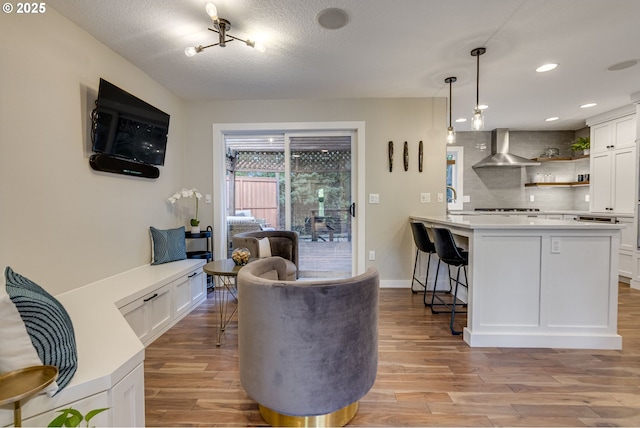 living area featuring light wood finished floors, baseboards, recessed lighting, and a textured ceiling