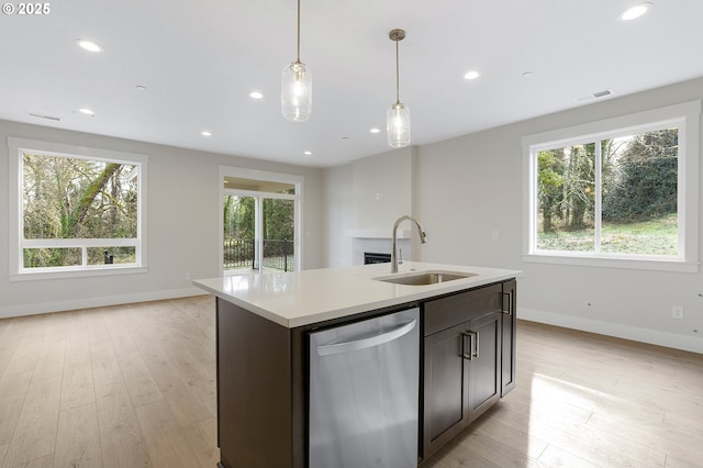 kitchen with sink, hanging light fixtures, dark brown cabinetry, an island with sink, and stainless steel dishwasher