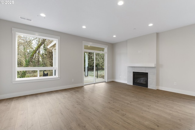 unfurnished living room with a tile fireplace and light wood-type flooring