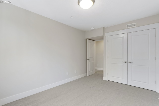 unfurnished bedroom featuring light colored carpet and a closet