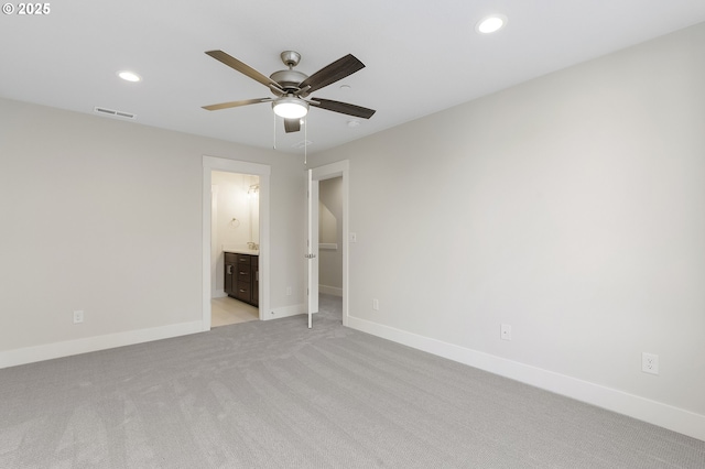 unfurnished bedroom featuring connected bathroom, a spacious closet, light colored carpet, and ceiling fan