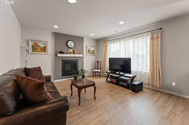 9465 N Alder St, Camas, WA 98607 - living area featuring recessed lighting, light wood-style floors, a glass covered fireplace, and a textured ceiling