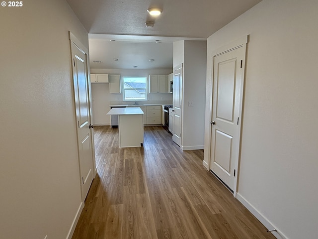 kitchen featuring a sink, baseboards, wood finished floors, and a center island