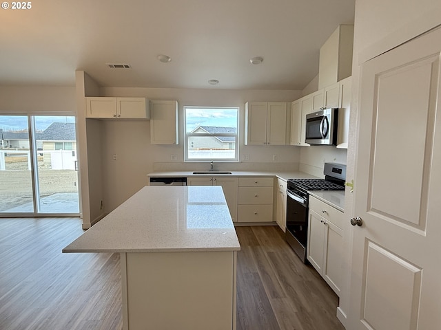 kitchen featuring a center island, visible vents, appliances with stainless steel finishes, a sink, and plenty of natural light