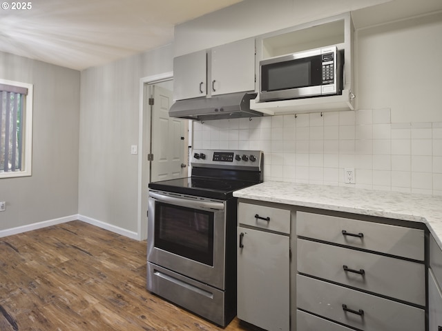 1818 E 32nd St, Vancouver, WA 98663 - kitchen with stainless steel appliances, under cabinet range hood, gray cabinetry, dark wood-style floors, and decorative backsplash