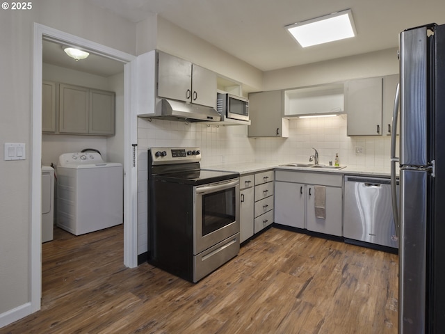 1818 E 32nd St, Vancouver, WA 98663 - kitchen featuring appliances with stainless steel finishes, under cabinet range hood, washing machine and dryer, decorative backsplash, and dark wood-style flooring