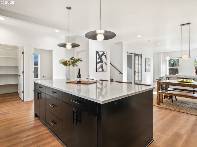 kitchen featuring a center island, a barn door, decorative light fixtures, and light hardwood / wood-style flooring