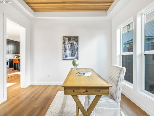 office area with hardwood / wood-style flooring and a raised ceiling