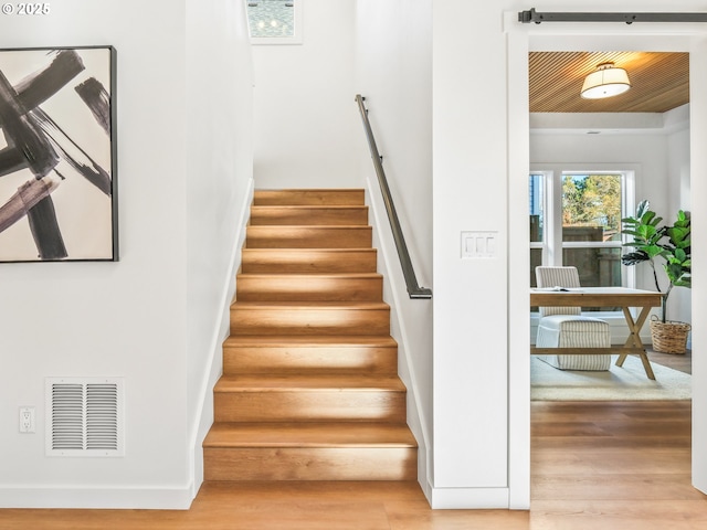 staircase with hardwood / wood-style flooring and wooden ceiling