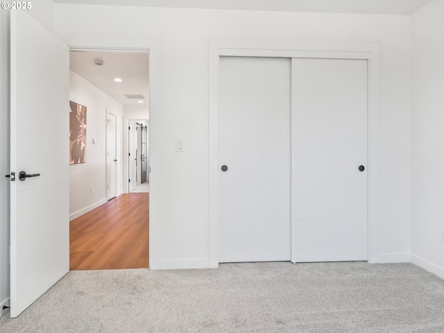 unfurnished bedroom with light colored carpet and a closet