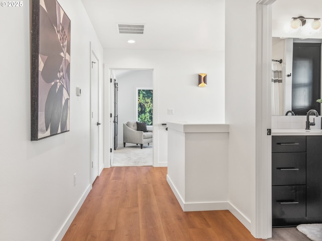 hall featuring sink and light hardwood / wood-style floors