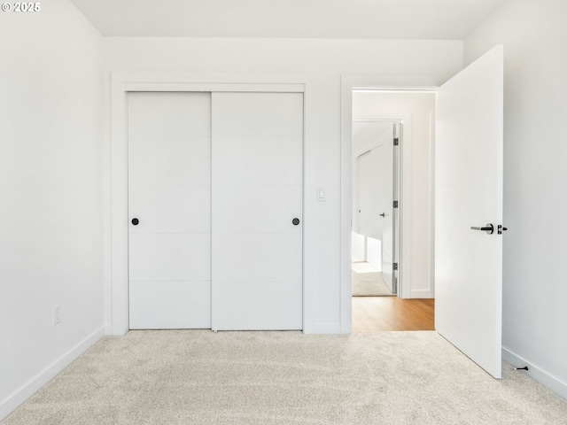 unfurnished bedroom with light colored carpet and a closet