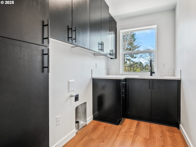 laundry area with cabinets, sink, and light hardwood / wood-style floors