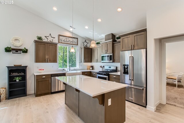 kitchen with stainless steel appliances, light wood finished floors, a kitchen island, tasteful backsplash, and lofted ceiling