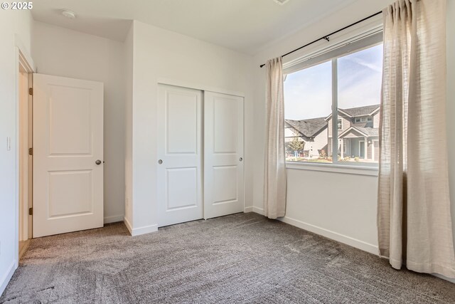 unfurnished bedroom featuring carpet, baseboards, and a closet