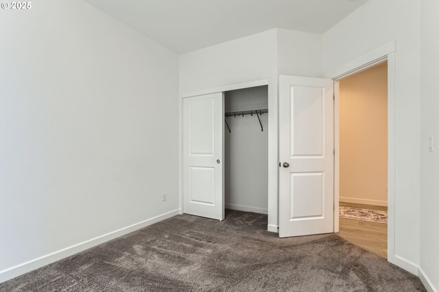 unfurnished bedroom featuring dark carpet, a closet, and baseboards