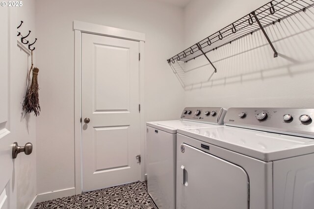clothes washing area with separate washer and dryer and baseboards