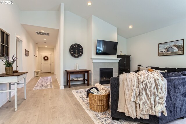 living room featuring vaulted ceiling, light wood-style floors, a fireplace, and recessed lighting