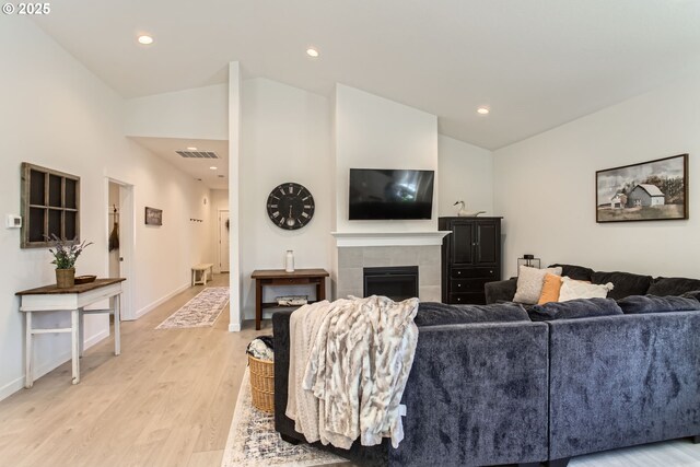 living area featuring lofted ceiling, light wood-type flooring, a fireplace, baseboards, and recessed lighting