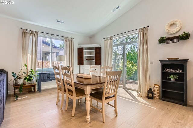 dining area featuring vaulted ceiling, plenty of natural light, and light wood-style floors