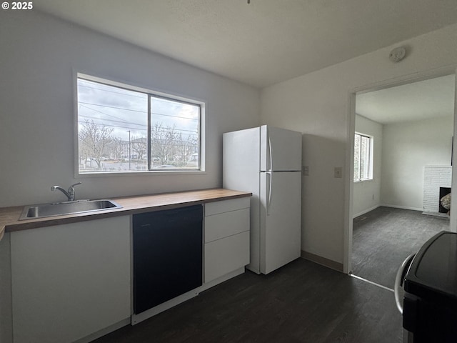 kitchen featuring dark wood finished floors, freestanding refrigerator, a sink, white cabinets, and dishwasher