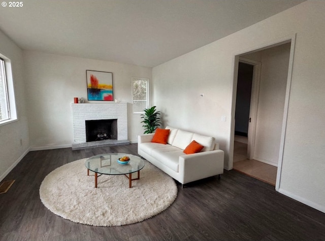 living area featuring baseboards, wood finished floors, and a fireplace