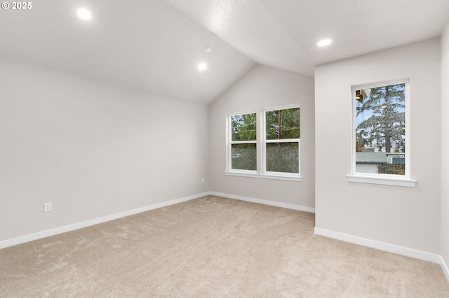 carpeted spare room with vaulted ceiling