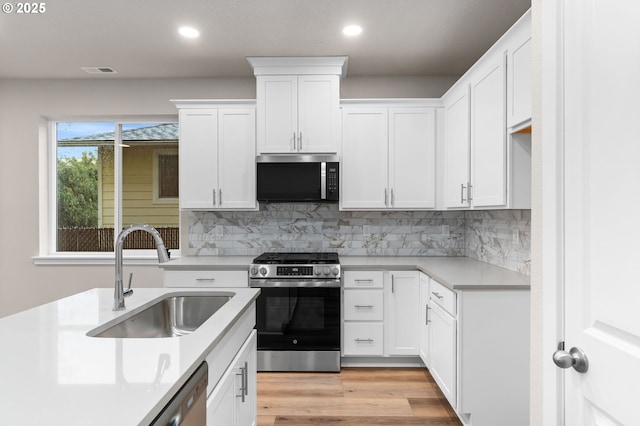 kitchen featuring appliances with stainless steel finishes, tasteful backsplash, white cabinetry, and sink