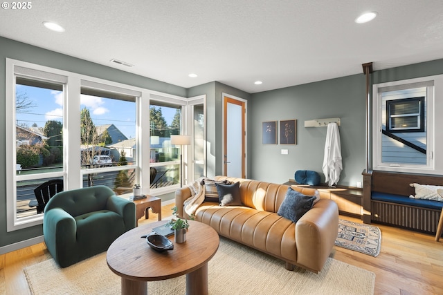 living room with radiator, a textured ceiling, and light wood-type flooring