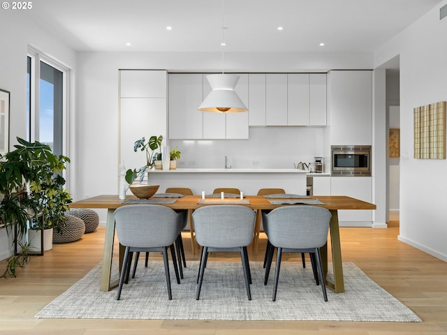 kitchen with stainless steel microwave, sink, light wood-type flooring, and white cabinets