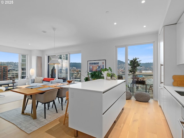 kitchen with white cabinetry, a healthy amount of sunlight, light hardwood / wood-style flooring, and decorative light fixtures