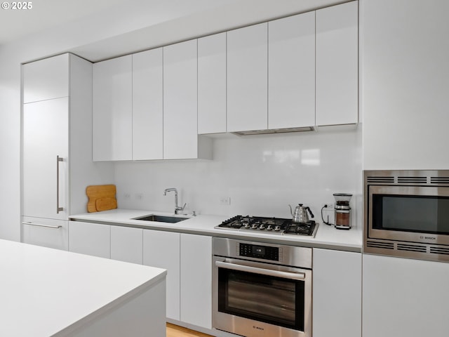 kitchen featuring stainless steel appliances, sink, and white cabinets