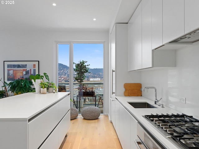 kitchen with sink, light hardwood / wood-style flooring, white cabinetry, stainless steel gas cooktop, and a mountain view