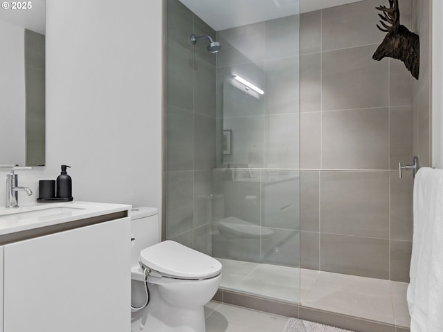 bathroom with tiled shower, vanity, and toilet