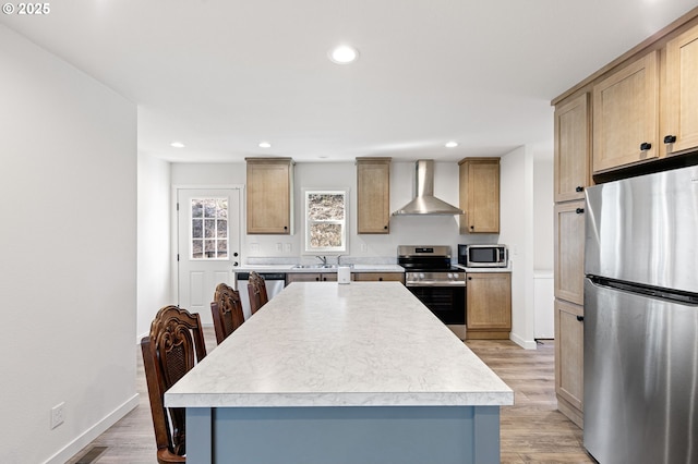 kitchen featuring appliances with stainless steel finishes, light wood-type flooring, wall chimney range hood, and a sink