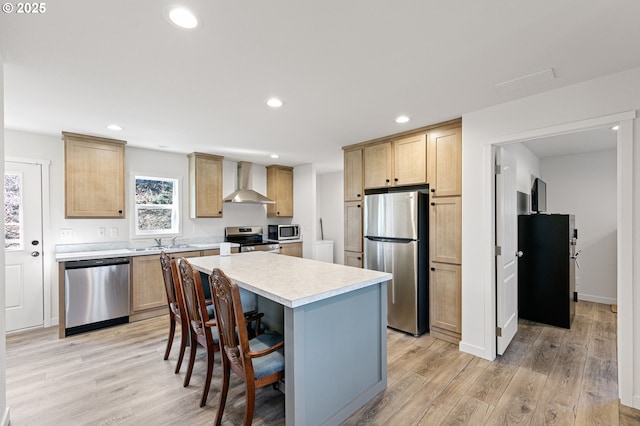 kitchen featuring light wood-style floors, stainless steel appliances, light countertops, and wall chimney range hood