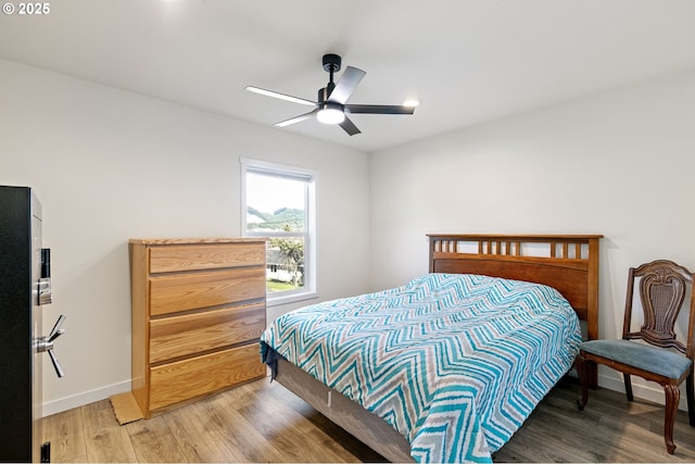 bedroom with a ceiling fan, light wood-style floors, and baseboards