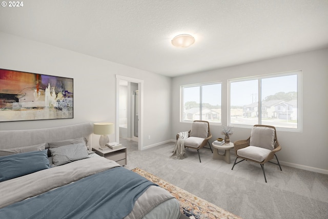 bedroom with ensuite bathroom and light colored carpet