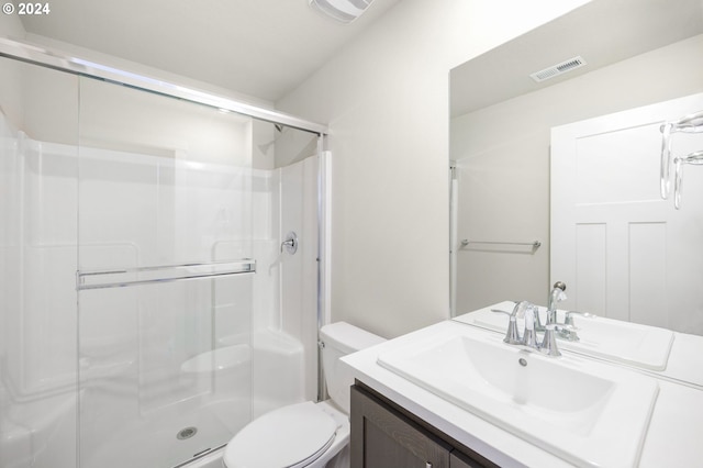 bathroom featuring vanity, a shower with shower door, and toilet