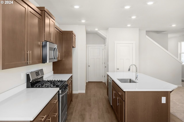 kitchen featuring a kitchen island with sink, sink, stainless steel appliances, and light hardwood / wood-style flooring