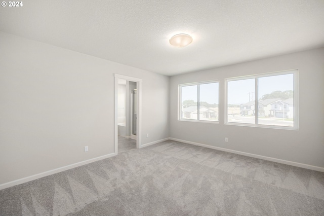 carpeted empty room featuring a textured ceiling