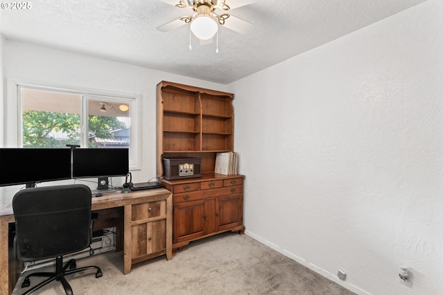 office space featuring light carpet, ceiling fan, and a textured ceiling