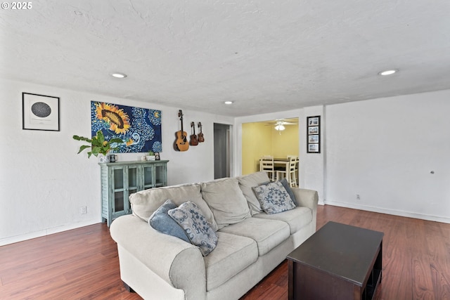 living room featuring ceiling fan, dark hardwood / wood-style floors, and a textured ceiling