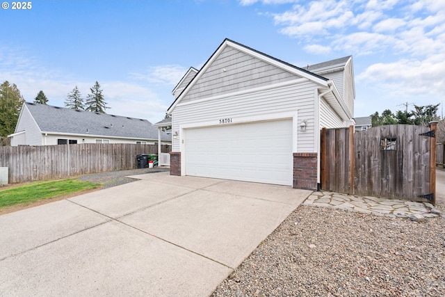 view of side of property with a garage, fence, concrete driveway, and brick siding