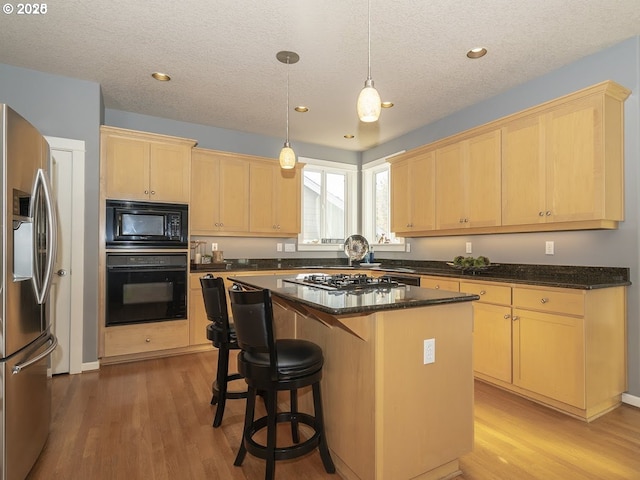 2600 Umpqua Ln, West Linn, OR 97068 - kitchen with black appliances, light brown cabinetry, light wood-type flooring, a center island, and a textured ceiling