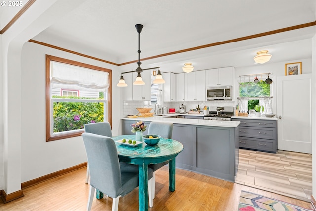 3416 SE 63rd Ave, Portland, OR 97206 - kitchen featuring stainless steel microwave, range, gray cabinets, healthy amount of natural light, and crown molding