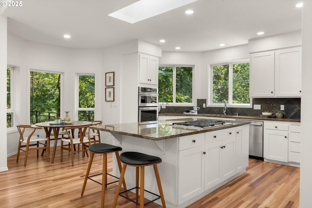 1911 NW Norfolk Ct, Portland, OR 97229 - kitchen with appliances with stainless steel finishes, a skylight, tasteful backsplash, light wood-style flooring, and recessed lighting