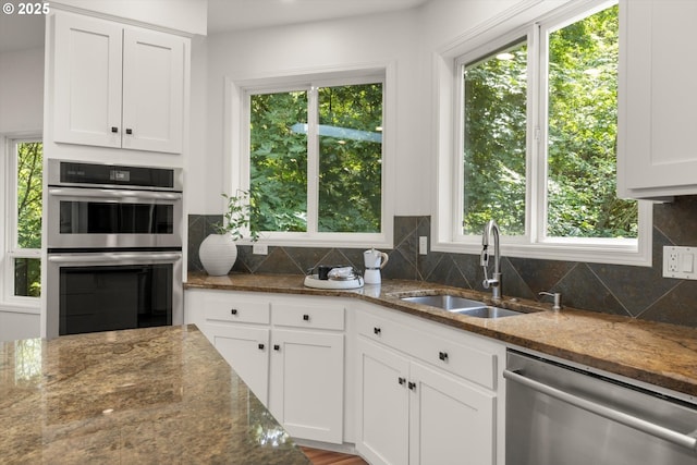 1911 NW Norfolk Ct, Portland, OR 97229 - kitchen with appliances with stainless steel finishes, white cabinets, dark stone counters, decorative backsplash, and plenty of natural light