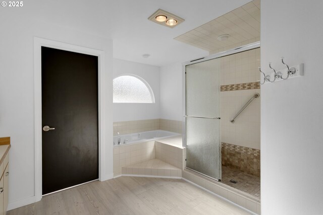 full bath featuring a bath, a tile shower, and wood finished floors